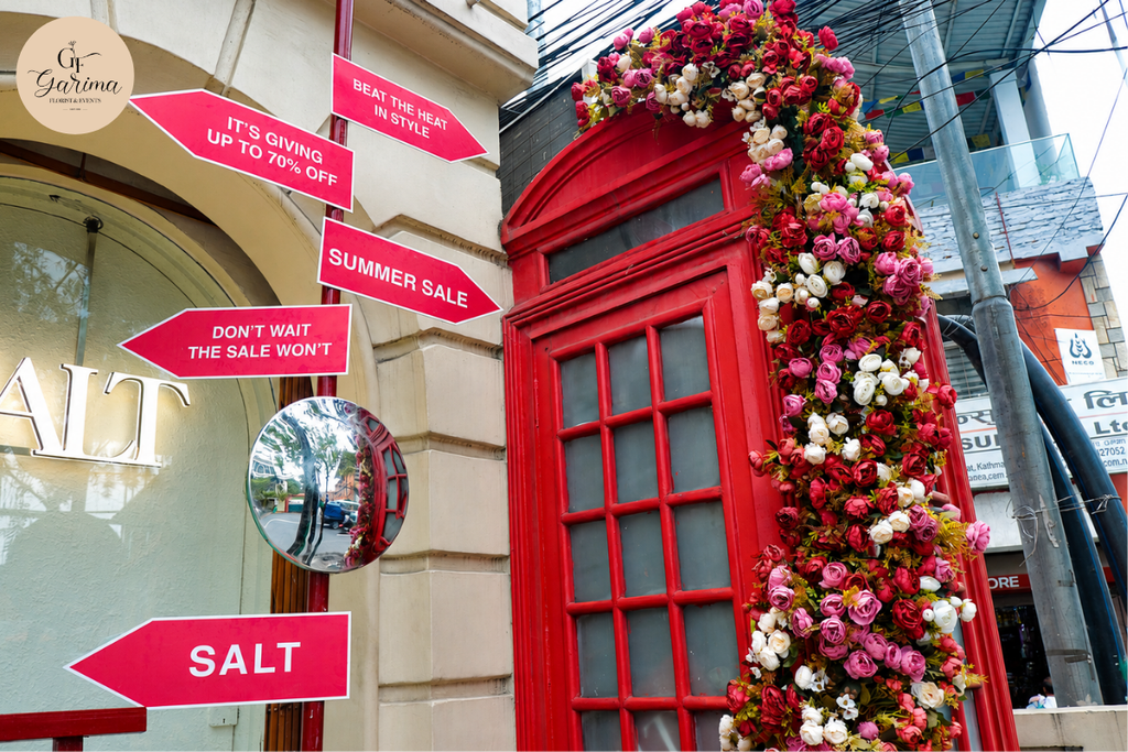 red and pink floral arch with colorful event signage outside a decorated venue in Kathmandu