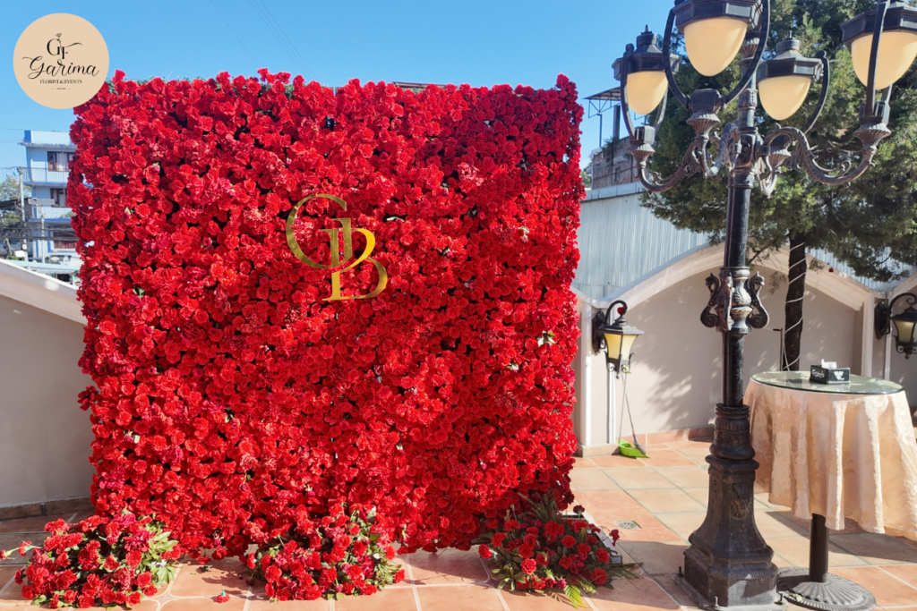red floral backdrop with coordinated branding, decorative frames, and floral arrangements for a private event