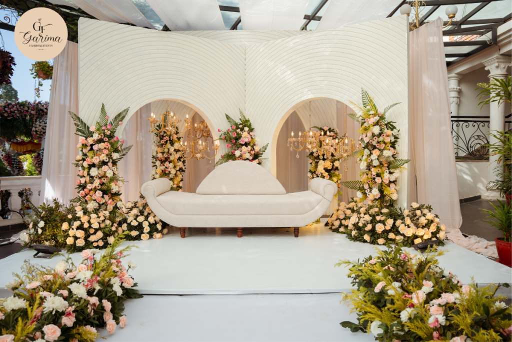elegant white wedding stage decorated with floral arrangements and chandeliers 