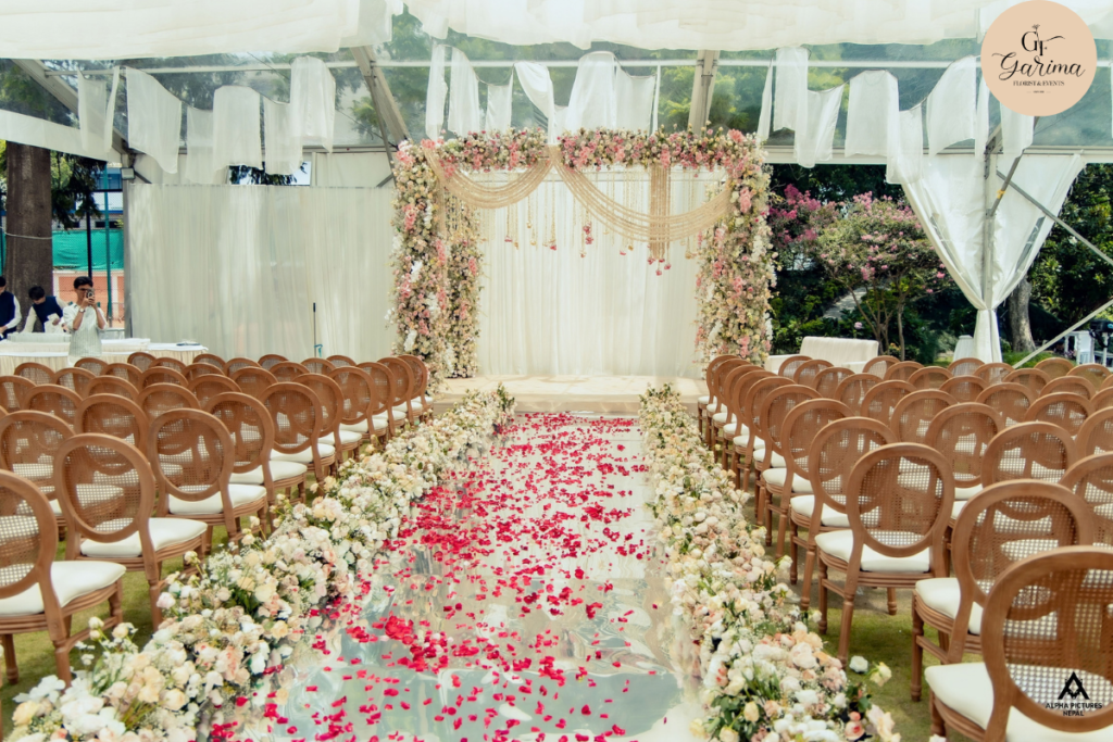 outdoor wedding ceremony setup with red floral aisle, stage and guest seating by garima florist & events