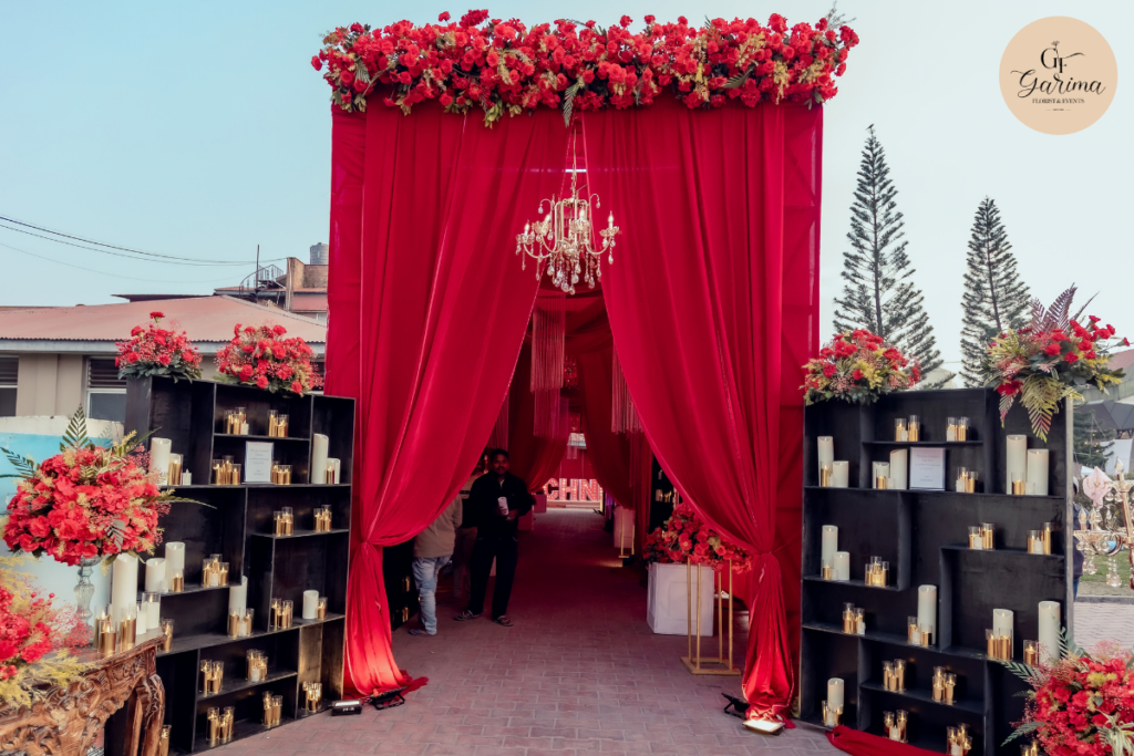 red floral wedding entrance decoration with draping, candles and chandelier